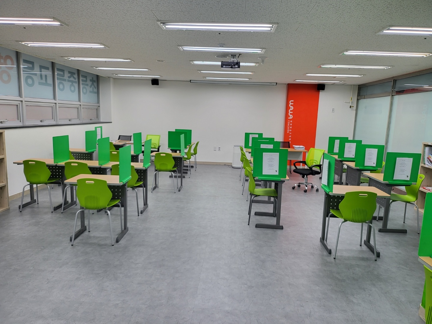 와와학습코칭 대구장기점 코칭 교실 — 초록색 가림판이 세워진 개인 책상들 사이에 선생님용 책상과 의자가 함께 놓여 있는 모습