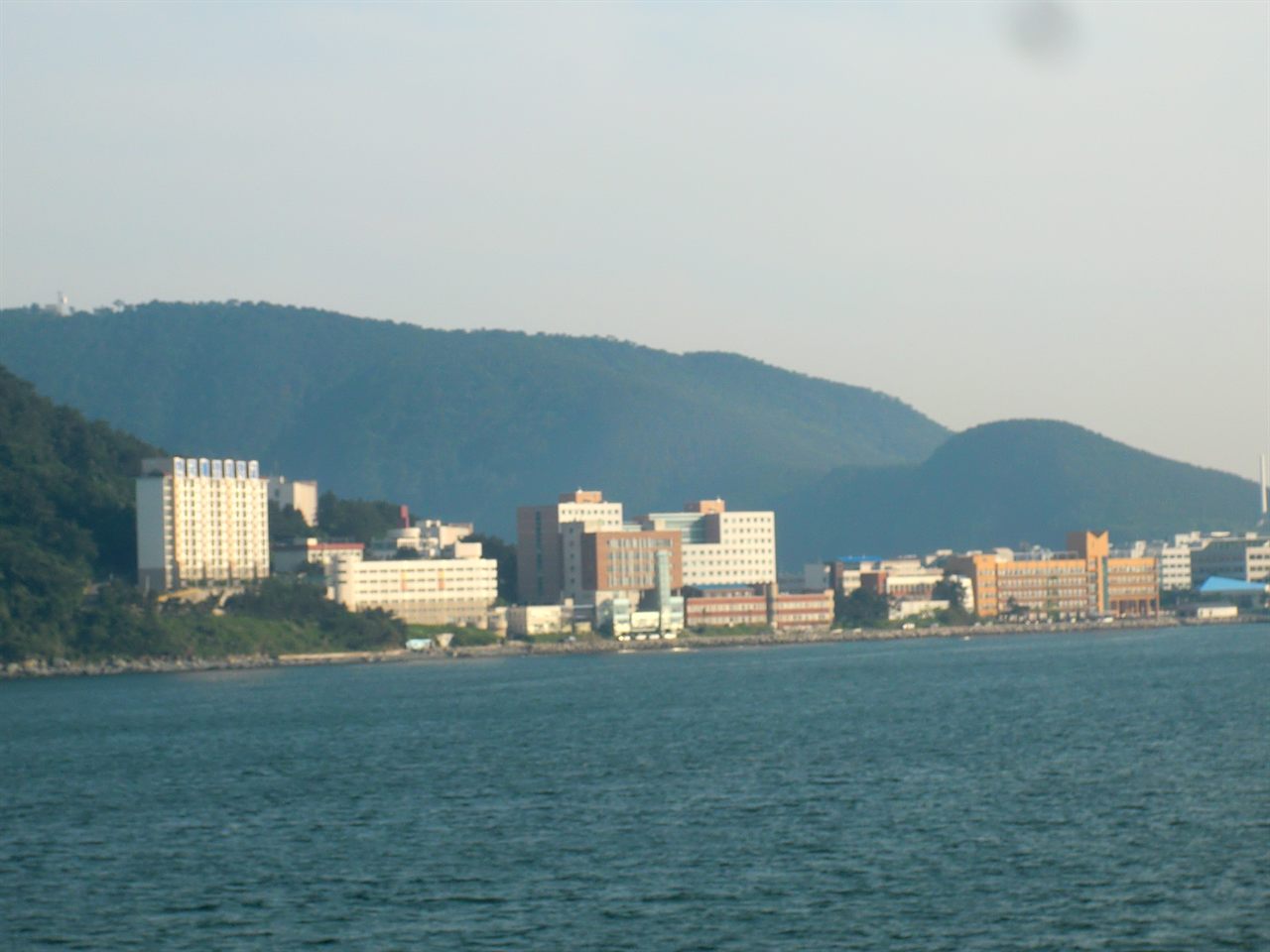 바다 건너에서 바라본 국립한국해양대학교 캠퍼스 — 부산 영도 앞바다 너머로 산자락 아래 캠퍼스 건물들이 해안선을 따라 줄지어 서 있다